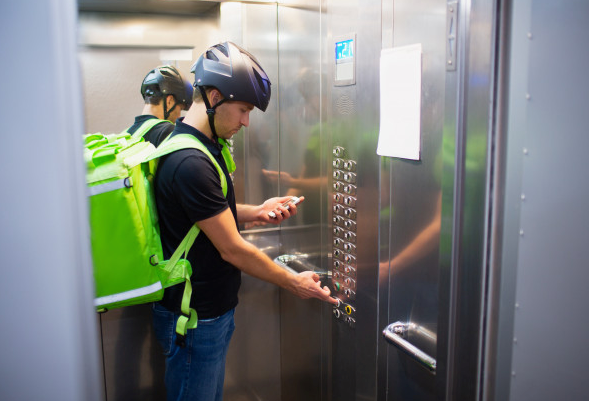 Un repartidor presiona el botón del  ascensor para dejar un paquete. / ARCHIVO