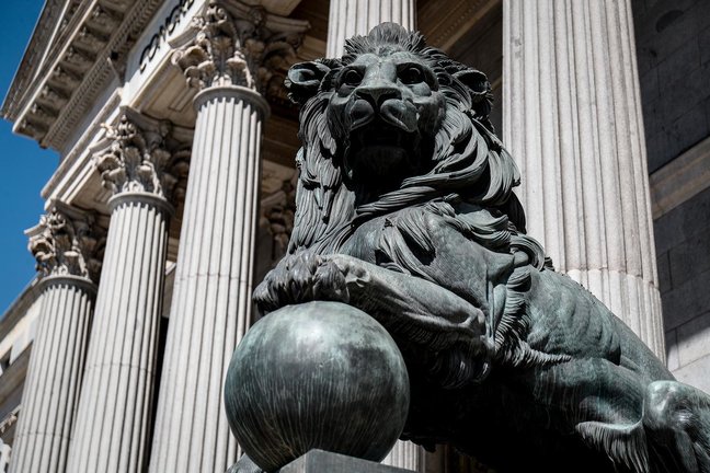 Archivo - Uno de los emblemáticos leones que se encuentran delante de la fachada del Congreso de los Diputados en la Plaza de las Cortes de Madrid.