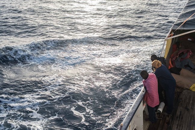 Archivo - Refugiados y migrantes miran por la borda en el Mediterráneo desde la borda del Open Arms tras un rescate.
