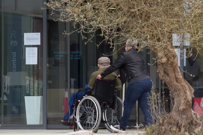 Archivo - Una mujer pasea junto a un anciano en silla de ruedas hacia una residencia en Lugo.