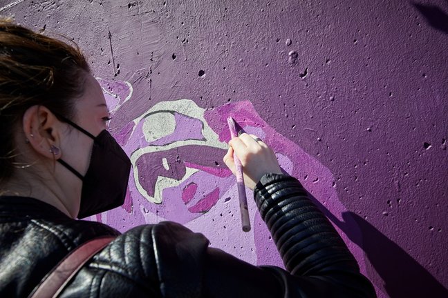 Archivo - Una mujer participa en la tarea de pintar de nuevo el mural feminista de Unlogic Crew en Getafe.
