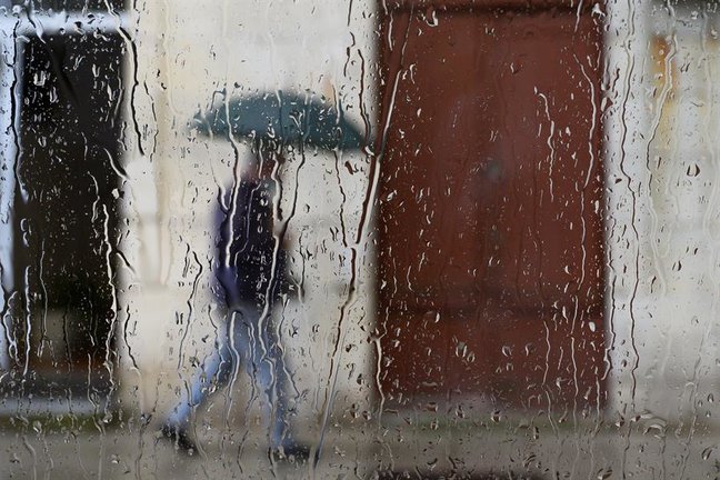 Un hombre camina bajo la lluvia por una calle de Santander, este viernes, cuando un frente atlántico dejará precipitaciones generalizadas en toda la Península. EFE/Pedro Puente Hoyos
