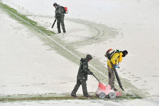 Empleados del Atalanta limpian las rayas del campo y las pintan de rojo para jugar con nieve.
ISABELLA BONOTTO (AFP)