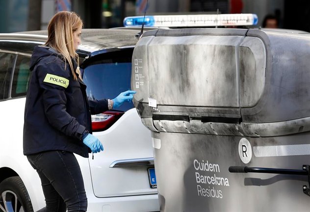 Una agente de los Mossos d'Esquadra realiza su trabajo en la calle Casanova con Avenida de Roma donde un vecino ha hallado el cadáver mutilado de una persona dentro de una maleta en un contenedor (i). EFE / Andreu Dalmau