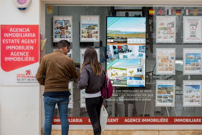 Una pareja se detiene a observar las propiedades en venta anunciadas en el escaparate de una agencia inmobiliaria. EFE / David Arquimbau