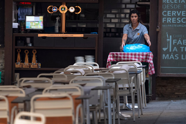 Una camarera coloca las mesas en un bar. / Ismael Herrero