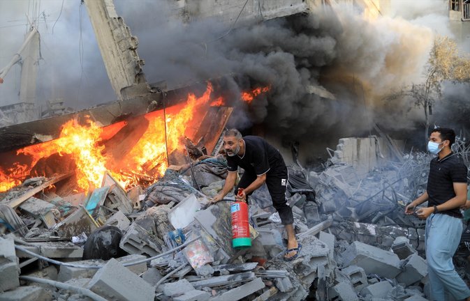Un hombre extinguiendo el fuego en pleno bombardeo