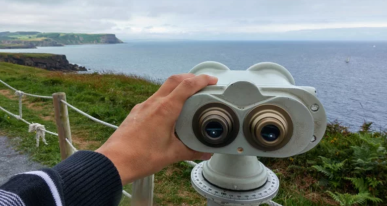 Un turista mira a través de unos prismáticos en la costa Cantábrica.