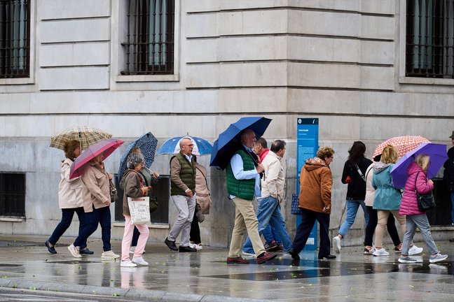 Varias personas se cubren de la lluvia y el viento con paraguas en una calle de Santander. EP