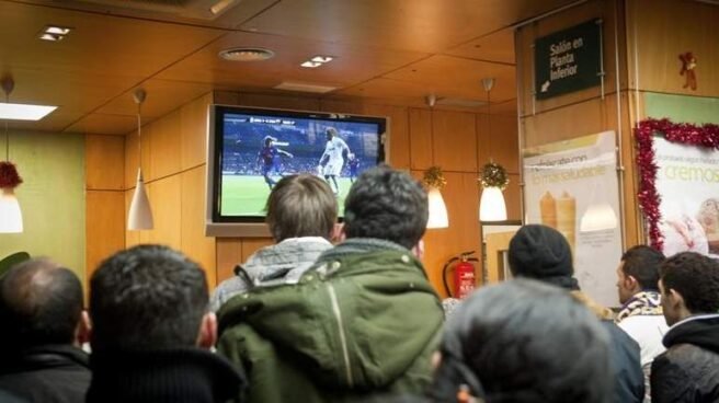 Un grupo de gente ve un partido de fútbol en la televisión de un bar. / EFE