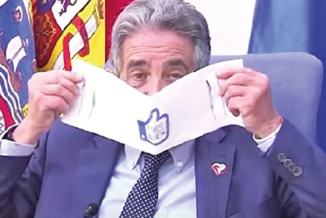 El entonces presidente. Miguel Ángel Revilla, se coloca una de las ‘revilletas’ que ofrecía como mascarillas. / ALERTA