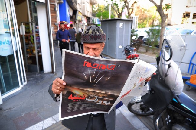 Un hombre en Teherán leyendo un periódico con la imagen de unos ataques. EP / Rouzbeh Fouladi