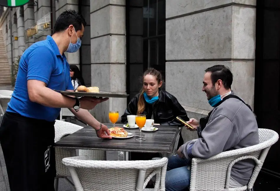 Dos j&oacute;venes son atendidos en la ma&ntilde;ana de hoy por un camarero en Santander. / J. Ram&oacute;n