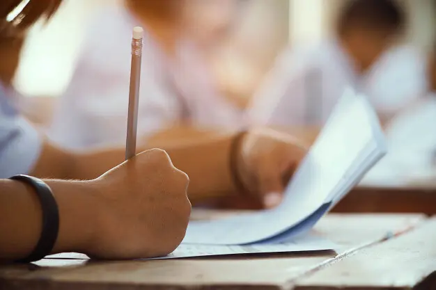 primer-plano-mano-estudiante-sosteniendo-lapiz-tomando-examen-aula-estres-prueba-educacion_73622-731