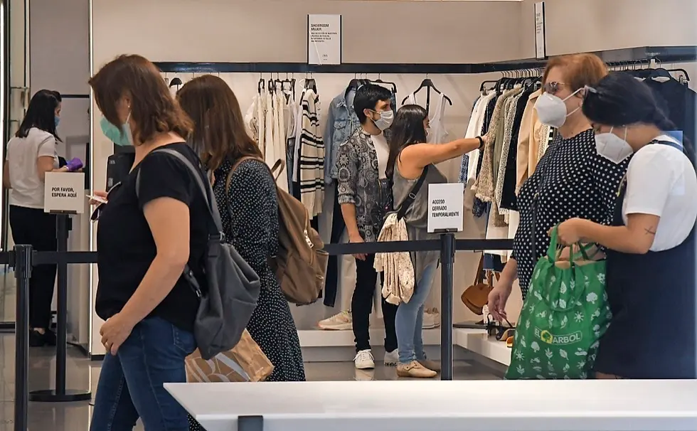 Varias personas comprando en una tienda de ropa. / Hardy