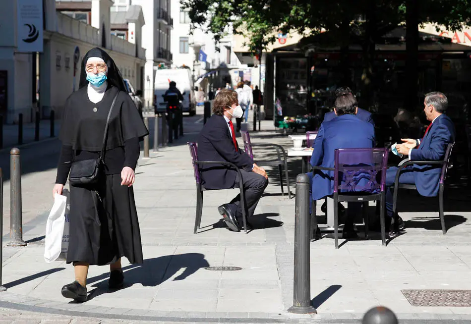 Una monja con mascarilla pasea por la calle Hern&aacute;n Cort&eacute;s de Santander.