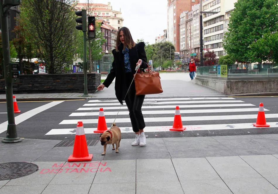 Una persona pasea por el paso de cebra junto a una pintada que se lee 'mantenga la distancia', en la calle Isabel II en Santander. / J. Ram&oacute;n