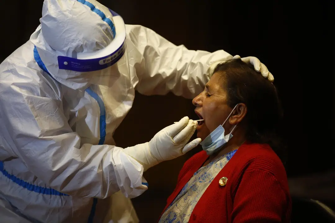 07 May 2020, Nepal, Kathmandu: A health worker takes a throat swab sample for the coronavirus PCR test from a woman, as the government is testing the members of National Assembly and House of Representatives for the novel coronavirus a day before the new 