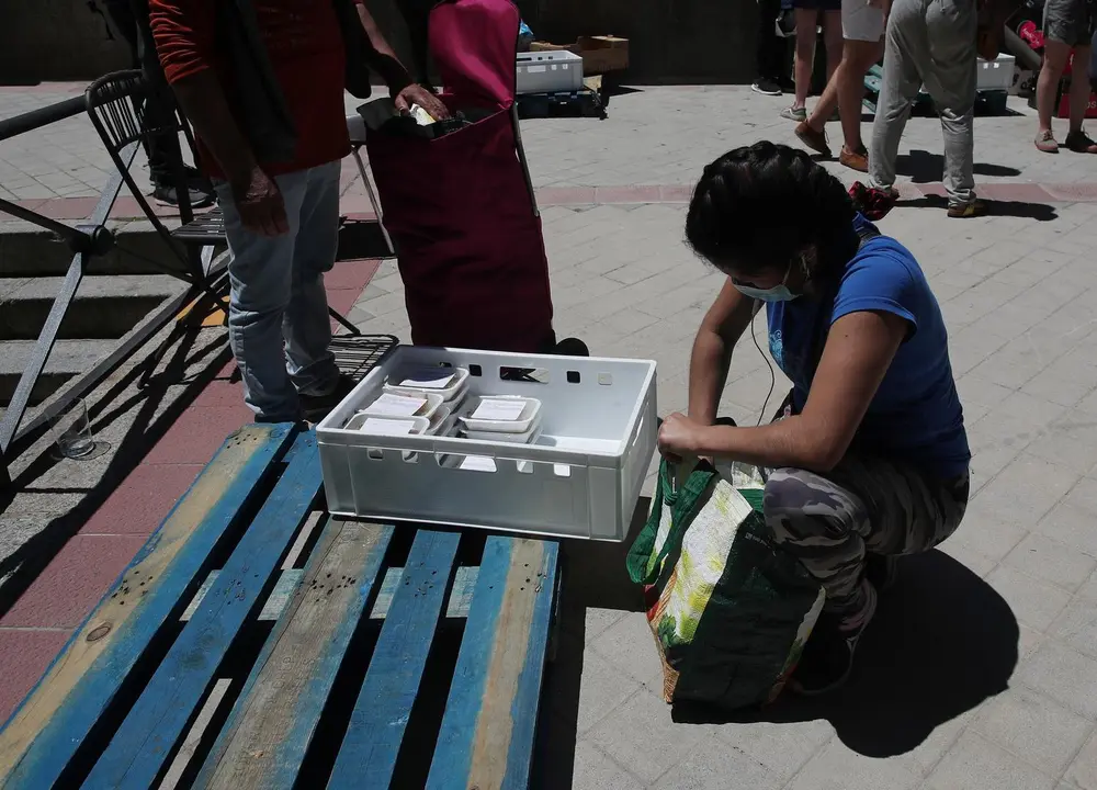 Una mujer recoge productos a las puertas de la Parroquia Santa Mar&iacute;a Micaela donde han acudido para recibir una ayuda alimentaria d