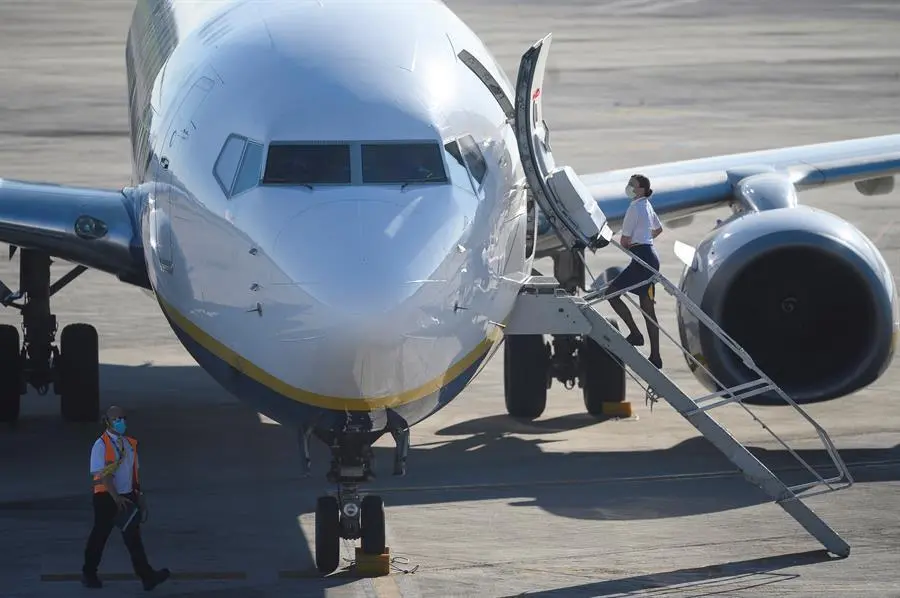 Una azafata sube a bordo de un avi&oacute;n de Ryanair, con destino Valencia, que ha sido el primero en despegar, este martes, del aeropuerto Seve Ballesteros en Malia&ntilde;o (Cantabria), tras tres meses sin actividad en el aeropuerto debido al coronavirus. EFE/Pedro Puente Hoyos