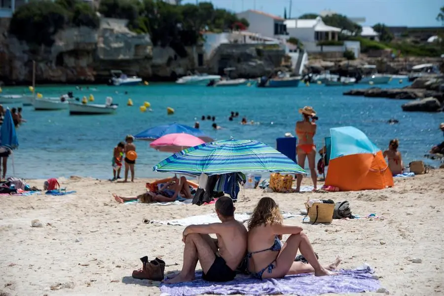 Varias personas disfrutan del sol y del agua en la cala de Alcalfar, Menorca, donde desde el mediod&iacute;a se ha activado la alerta amarilla por calor.EFE/ David Arquimbau Sintes