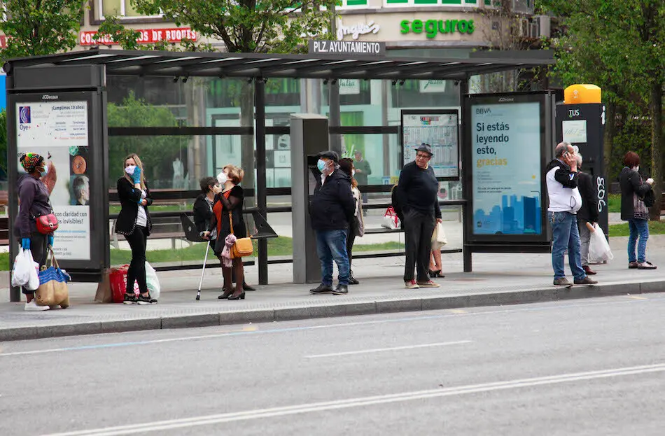 Varias personas con mascarilla esperan al autob&uacute;s en Santander. / J.R.