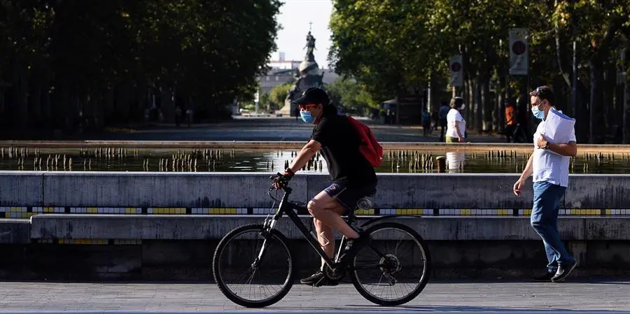 Un hombre circula en bicicleta y con mascarilla por el centro de la ciudad de Valladolid donde este viernes las temperaturas superar&aacute;n los 35 grados cent&iacute;grados. EFE/ Nacho Gallego