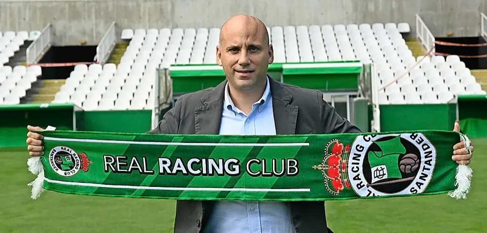 Javier Rozada posa con la bandera del Racing en Los Campos de Sport durante su primer acto p&uacute;blico como entrenador del equipo verdiblanco. / hardy