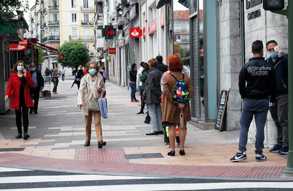 Varias personas con mascarilla hacen cola para entrar al banco. / J. R.