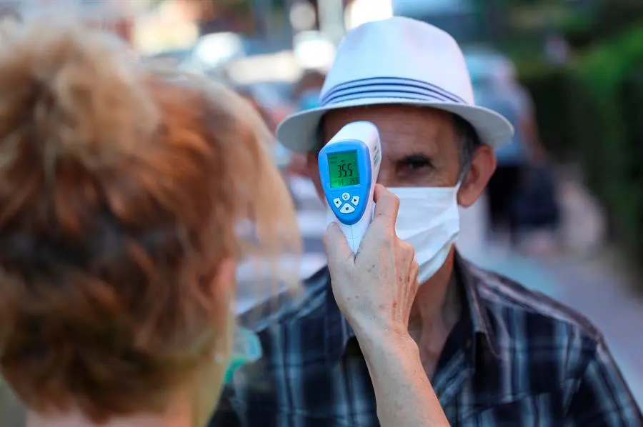 Una voluntaria de una asociaci&oacute;n de mayores toma la temperatura a un anciano. EFE/Rodrigo Jim&eacute;nez/Archivo