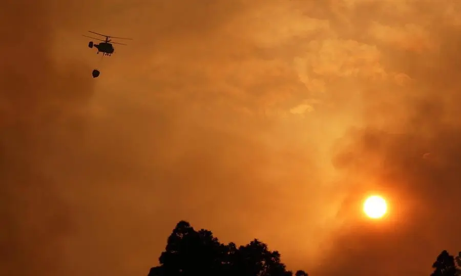 Un helic&oacute;ptero colabora en los trabajos extinci&oacute;n del incendio declarado en el municipio palmero de Garaf&iacute;a este s&aacute;bado. Vecinos de los barrios de Cueva del Agua y El Castillo, en Garaf&iacute;a (La Palma) han sido evacuados de manera preventiva por el incendio forestal que afecta desde ayer al municipio, y que sigue activo con tres frentes. EFE/MIGUEL CALERO