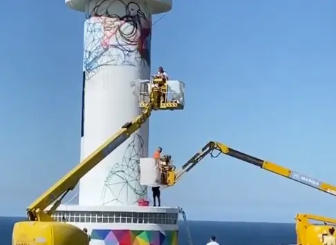 El artista Okuda y sus colaboradores realizando la obra en el Faro de Ajo.