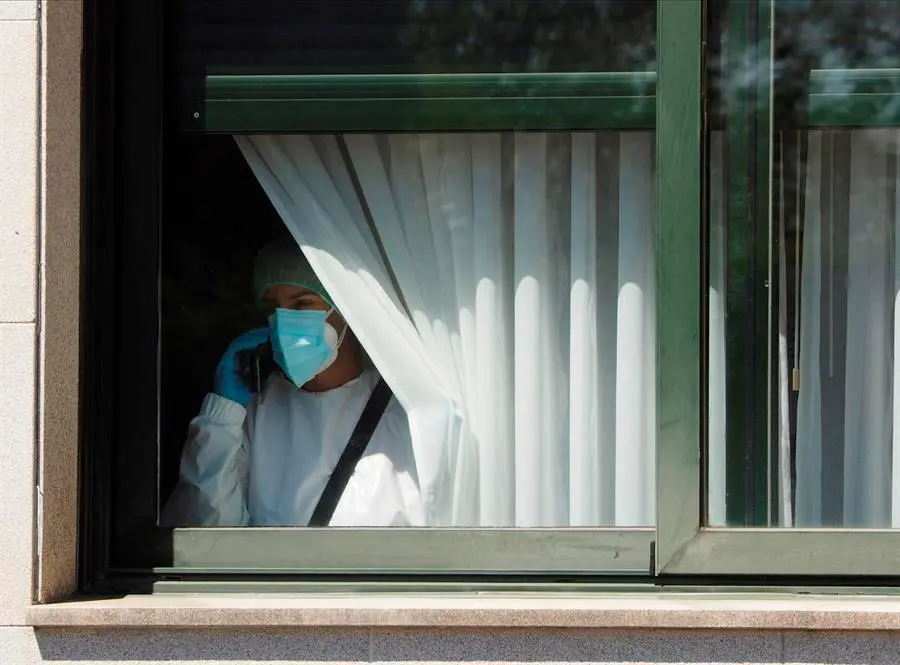 Una trabajadora sanitaria habla por tel&eacute;fono este s&aacute;bado desde el interior de la residencia de O Inicio (Lugo). EFE/Eliseo Trigo/Archivo