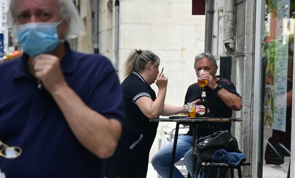 Una persona con mascarilla y al fondo una pareja tomando un refrigerio en una cafeter&iacute;a de Santander. / HARDY