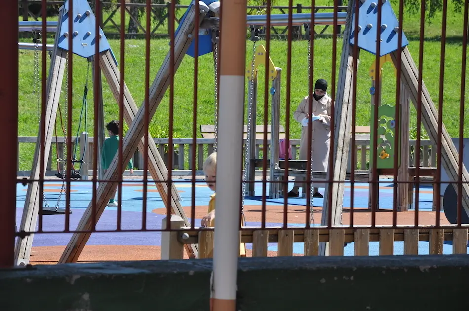 Una madre juega con su hijo en el parque junto al CEIP Jos&eacute; Mar&iacute;a Pereda en Torrelavega. / S.D.