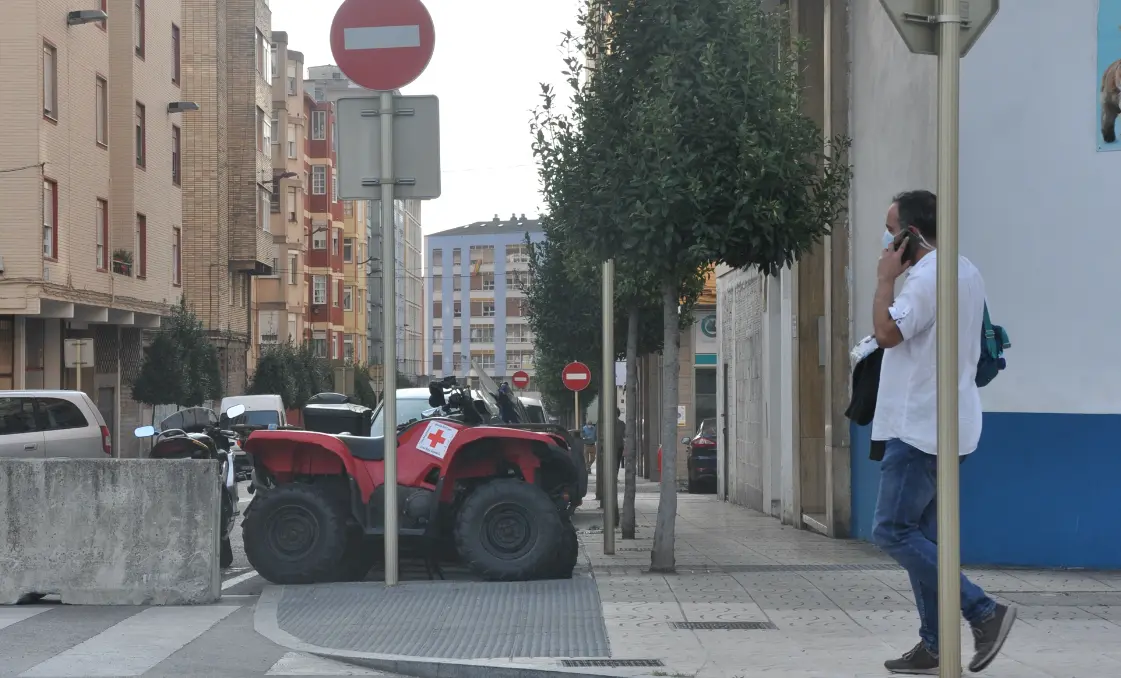 Una persona pasa delante de la barrera en la entrada del barrio de La Inmobiliaria en Torrelavega. / S.D.