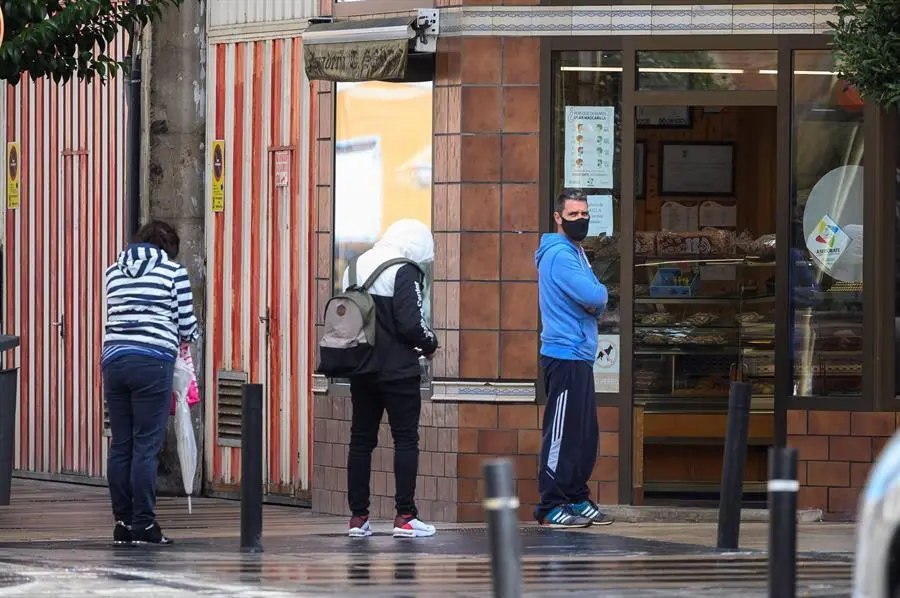 Varias personas esperan en la entrada de la Panader&iacute;a Sordo en el barrio de La Inmobiliaria en Torrelavega. / Pedro Puente Hoyos