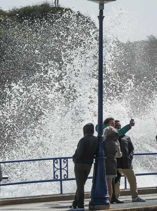 Varios j&oacute;venes se fotograf&iacute;an cerca de la costa tras romper una ola. / HARDY