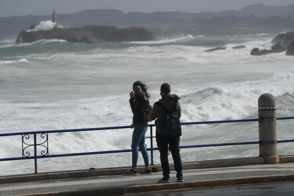Dos j&oacute;venes se fotograf&iacute;an en con el mar cantabrico de fondo en la playa del Sardinero. / HARDY