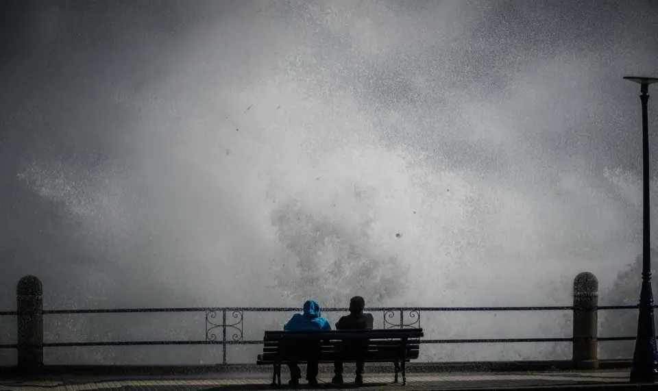 Dos personas contemplan el fuerte oleaje desde un banco en El Camello, durante el temporal que azot&oacute; Santander.
Foto: Nacho Cubero
