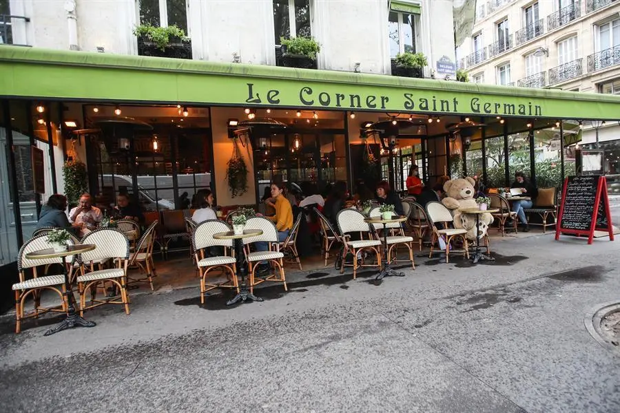 Personas sentadas en la terraza de un bar con mesas dispuestas para garantizar el distanciamiento social entre personas. EFE