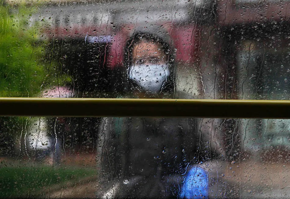 Una persona con mascarilla y guantes espera al autob&uacute;s en una parada en Santander. / J.R.