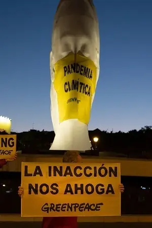 Activistas de Greenpeace han colocado una mascarilla giganteen una escultura de la plaza de Col&oacute;n (Madrid) en la que se lee "Pandemia Clim&aacute;tica".