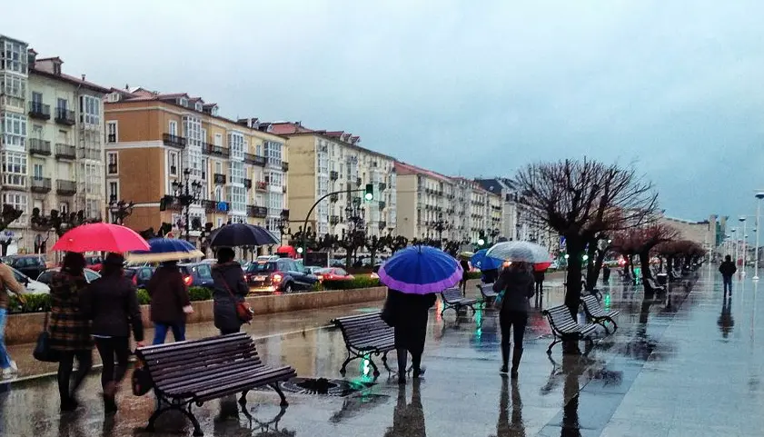 Varias personas caminan por el Paseo Pereda de Santander con sus paraguas. / eltomavistasdesantander