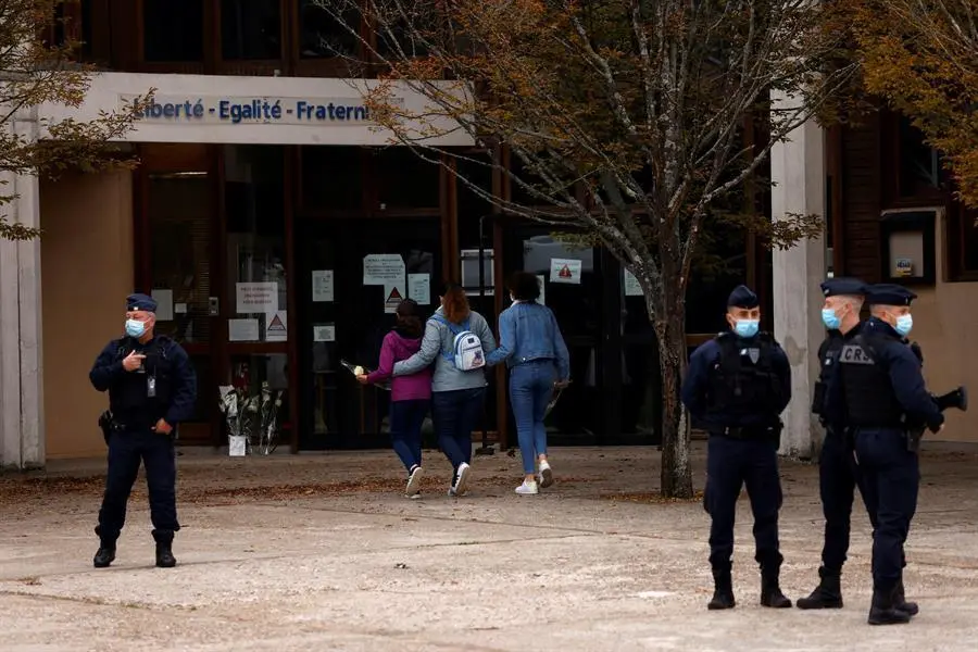 Los adolescentes llegan a depositar flores frente a la escuela secundaria Bois d'Aulne para presentar sus respetos despu&eacute;s del asesinato de un maestro en Conflans Saint-Honorine, en las afueras de Par&iacute;s. / EFE