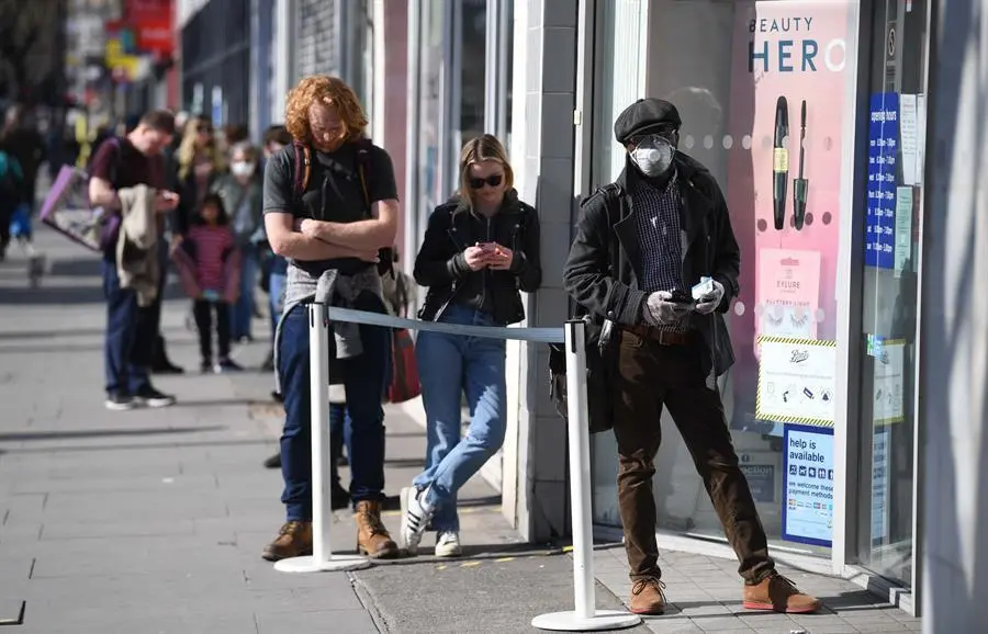 La gente mantiene medidas de distanciamiento social mientras hacen cola para una tienda en Londres, Gran Breta&ntilde;a. EFE/EPA/NEIL HALL/Archivo