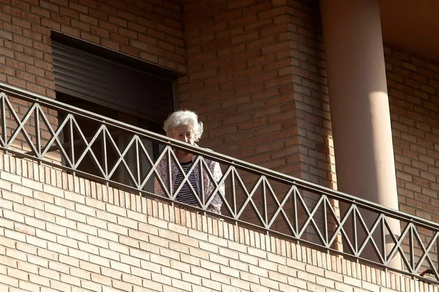 Una mujer este lunes en el balc&oacute;n de su habitaci&oacute;n de la residencia de mayores Ballesol, situada en la urbanizaci&oacute;n Altorreal de Molina de Segura (Murcia),que ha sido intervenida por el Servicio Murciano de Salud (SMS) al detectarse un brote con 79 casos positivos (69 residentes y 10 trabajadores) y el fallecimiento de uno de los afectados. EFE/ Marcial Guill&eacute;n