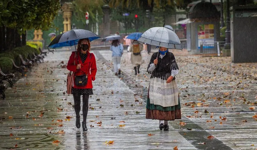 Dos mujeres pasen bajo la lluvia en el paseo de Los &Aacute;lamos, en el centro de Oviedo. Asturias y ocho comunidades mas, est&aacute;n hoy en alerta meteorol&oacute;gica, por viento y intensa lluvia, que podr&iacute;a dejar hasta 40 litros por metro cuadrado en 12 horas, y fuertes olas en el litoral. EFE/ Alberto Morante