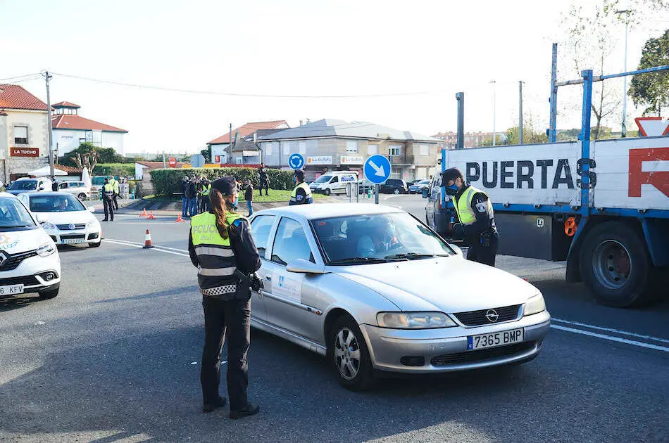 Un ciudadano con su veh&iacute;culo para junto al agente en un control realizado hoy en Corb&aacute;n, Santander. / ALERTA