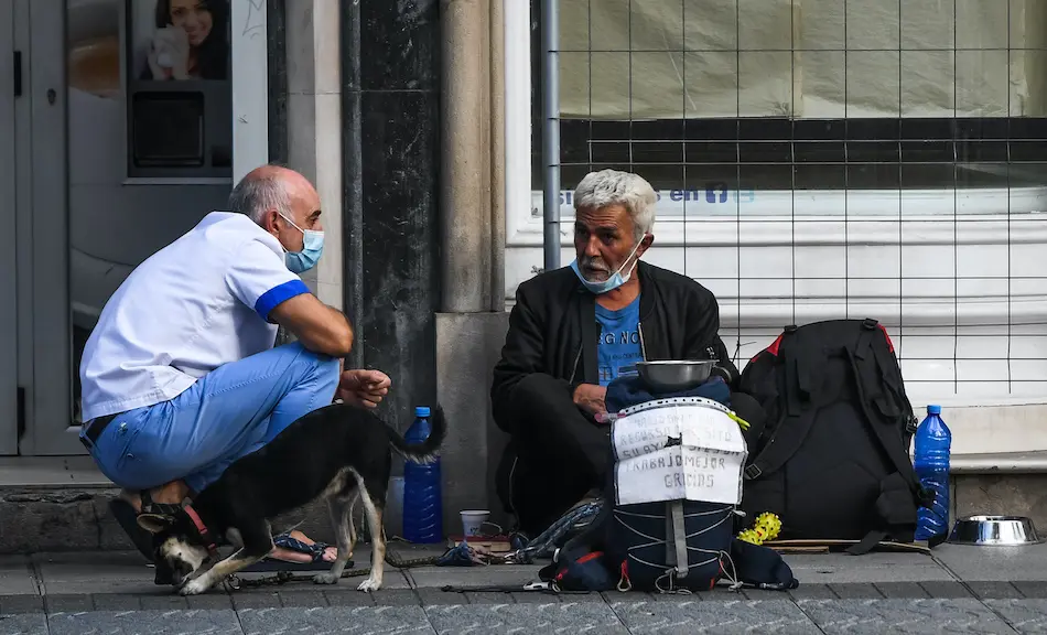 Una persona charla con otra que est&aacute; pidiendo ayuda en la calle la pasada semana, Santander. / Hardy
